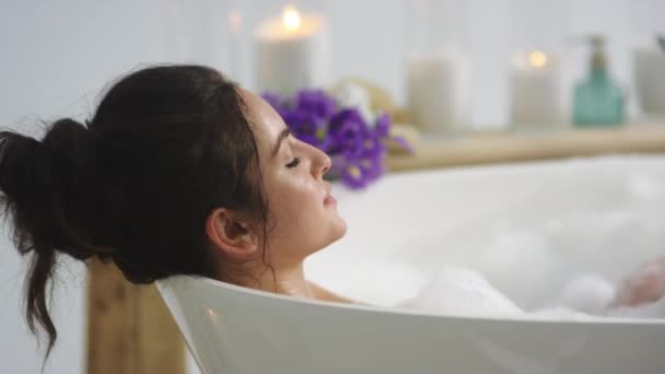 Primo piano donna rilassata soffiando schiuma in bagno. Sexy ragazza lavaggio mani in bagno — Video Stock