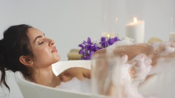 Primo piano donna rilassata lavaggio corpo con schiuma a bagno di casa. Donna che soffia schiuma — Video Stock