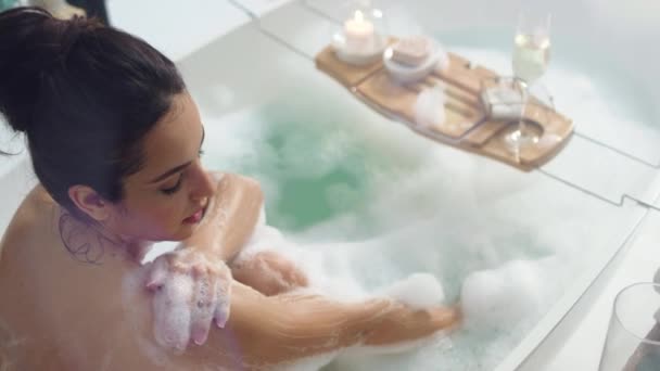 Улыбающаяся женщина моет руки пеной. Сексуальная девушка расслабляется в ванной со свечами — стоковое видео
