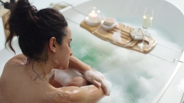 Расслабленная женщина касается кожи пеной. Чувственная девушка массирует свое тело в ванне — стоковое видео