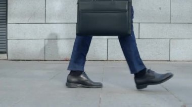 Şehir caddesinde yürüyen iş adamı bacakları. Evrak çantalı işçi işe gidiyor.