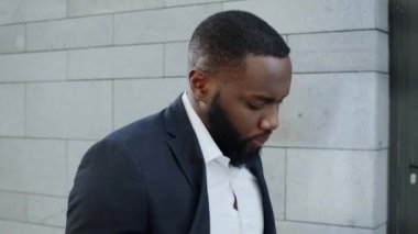 Şehir caddesinde yürüyen düşünceli bir işadamı. Çalışanlar caddeye bakıyor.