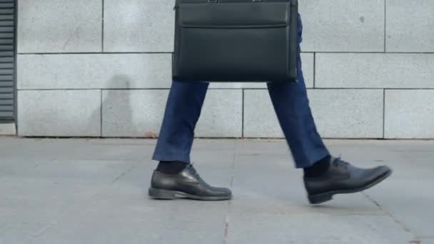 Üzletember lábak sétálnak a város utcáin. Munkavállaló aktatáskával munkába menet — Stock videók