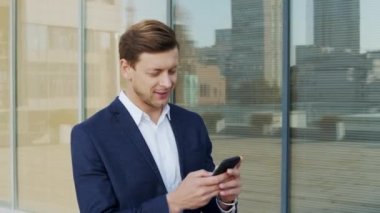 İş adamı sokakta cep telefonuyla yazı yazıyor. Çalışan kaldırımda iş arıyor.