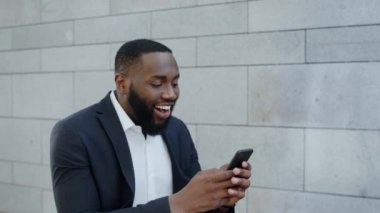 Afrikalı işadamı telefonda iyi haberler okuyor. Çalışanlar zaferi kutluyor.