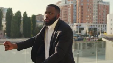 Sokakta başarılı bir anlaşmadan sonra Afro Adam dans ediyor. İş adamı kameraya bakıyor.