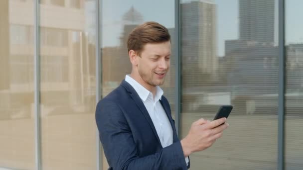 Verrast zakenman ontvangt goed nieuws op smartphone op straat — Stockvideo