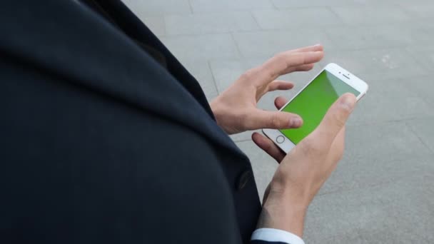 Бизнесмен, использующий мобильный телефон на городской улице. Рабочий прокручивает смартфон снаружи — стоковое видео