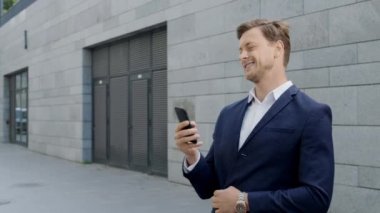 İş adamı sokakta akıllı telefon kullanıyor. Girişimci dışarıda zaferi kutluyor.