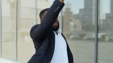 Şehir caddesinde dans eden Afro iş adamı. Çalışanlar dışarıda başarının tadını çıkarıyorlar.