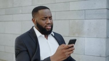 Afrikalı işadamı telefonda kötü haberler alıyor. Sokakta yürüyen bir iş adamı