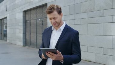 İş adamı şehirdeki tablette internete göz atıyor. İşçi sokakta ped kullanıyor.