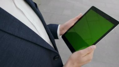 Sokaklarda dijital tablet üzerinde çalışan bir iş adamı. Çalışanların tuttuğu yer dışarıda.