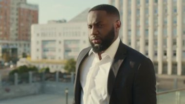 Sokakta yürüyen bir iş adamı. Takım elbiseli bir iş adamı dışarıdaki kameraya bakıyor.
