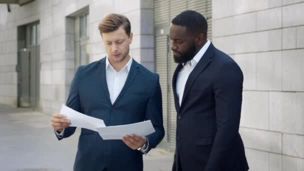 Empresarios mirando documentos en la calle. Hombres de negocios discutiendo gráficos — Vídeos de Stock