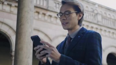 Öğrenci telefonda iyi haberler okuyor. İş adamı akıllı telefondan internete göz atıyor