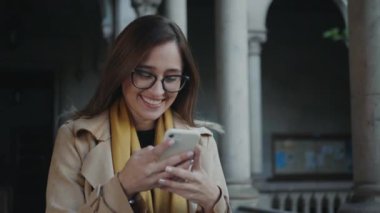 Öğrenci koridorda akıllı telefon kullanıyor. İş kadını dışarıda cep telefonuyla yazı yazıyor.