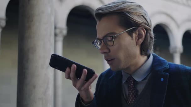 Estudiante grabando mensaje de voz en el teléfono celular. Hombre usando el teléfono móvil al aire libre — Vídeo de stock