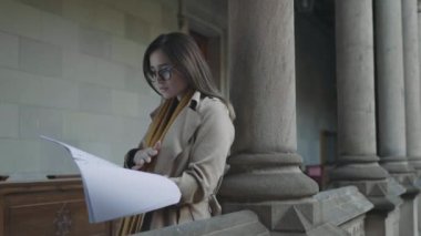 Öğrenci üniversitede not defterinde notlar okuyor. İş kadını çalışma kitabına bakıyor
