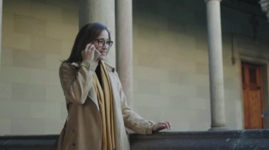 Öğrenci koridorda akıllı telefondan konuşuyor. İş kadını dışarıda telefonla arıyor.