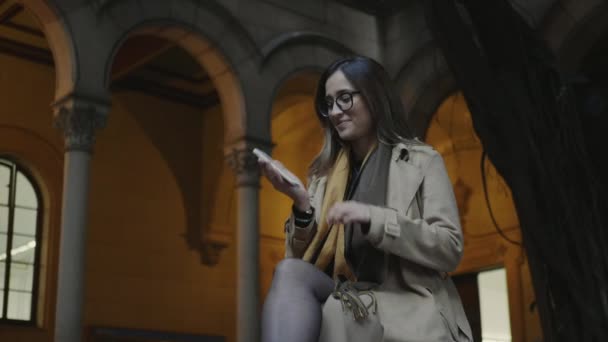 Studenten pratar på smartphone på universitetet. Kvinnan får goda nyheter på telefon — Stockvideo