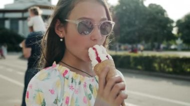 Dondurma yiyen güzel kız. Rahatlamış genç kız lunaparkta yürüyor.