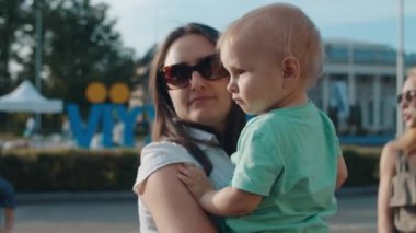 Elinde çocuğu olan genç bir kadın. Güzel anne ve bebek lunaparkta