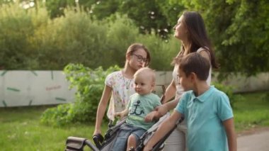 Rahat anne üç çocukla yürüyor. Mutlu aile yaz parkında dinleniyor.