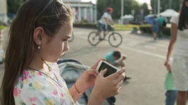 Parkta cep telefonuyla oynayan ciddi bir kız. Dışarıda telefonu kullanan tatlı bir kız.