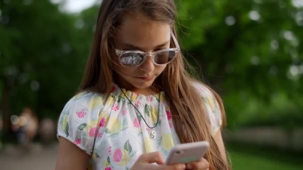Primer plano de chica seria jugando juegos en el teléfono. Chica con teléfono en el parque de verano — Vídeos de Stock