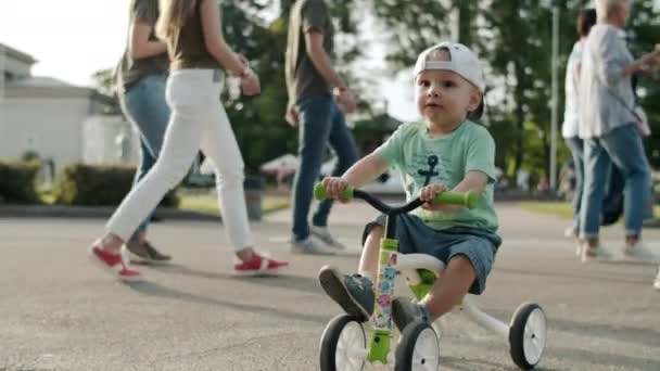 遊園地の幼児に焦点を当てた。小さな子供が最初に外の自転車で試してみる — ストック動画