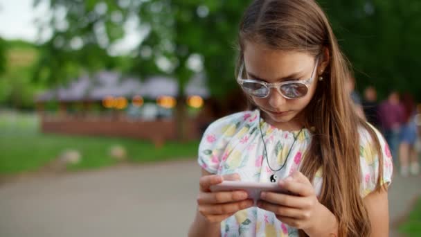 Akıllı telefon görünümlü konsantre genç kız. Ciddi kız cep telefonundan haber okuyor. — Stok video