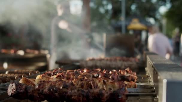 Shish kebabs preparing on skewers outdoors. Chef male cooking meat outside — Stock Video