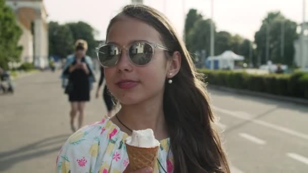 Nyugodt lány sétál a vidámparkban. Tini lány eszik fagylalt kúp — Stock videók