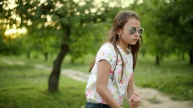 Ciddi bir genç kız dışarıda dans ediyor. Kız dışarıda ritmik hareketler yapıyor.