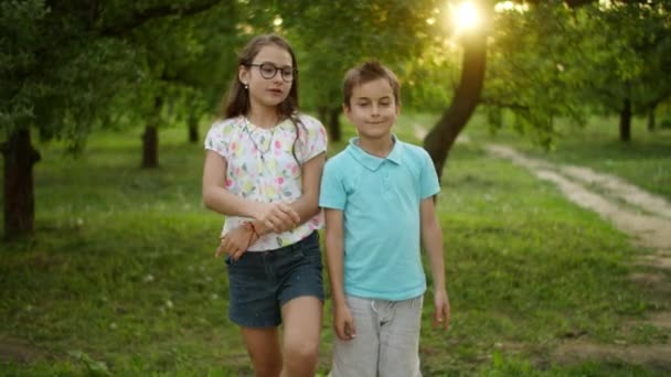 Irmão e irmã sorridentes dançando ao ar livre. Bonito crianças no parque de verão — Vídeo de Stock