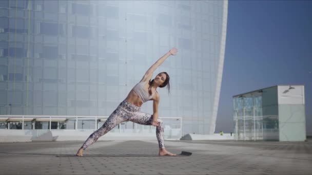 Menina realizando ioga na rua. Mulher fazendo pose de ângulo lateral estendido na rua — Vídeo de Stock