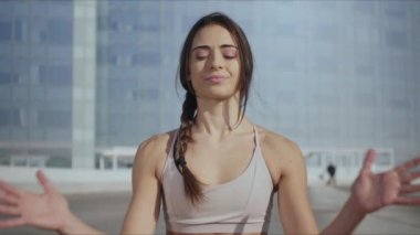 Nilüfer çiçeğinde oturan gülümseyen kadın şehir sokaklarında poz veriyor. Açık havada meditasyon yapan sağlıklı bir kız.