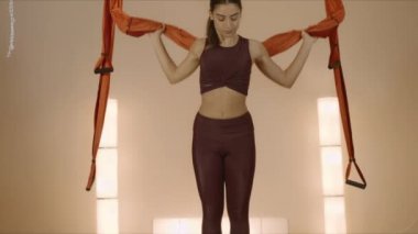Stüdyoda hamakta vücudu ısıtan bir kız. Kadın içeride yoga yapıyor.