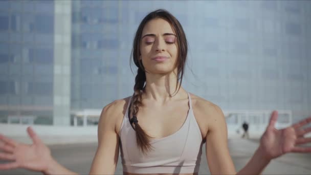 Usmívající se žena sedí v lotosu pózovat na městské ulici.fit dívka medituje venku — Stock video