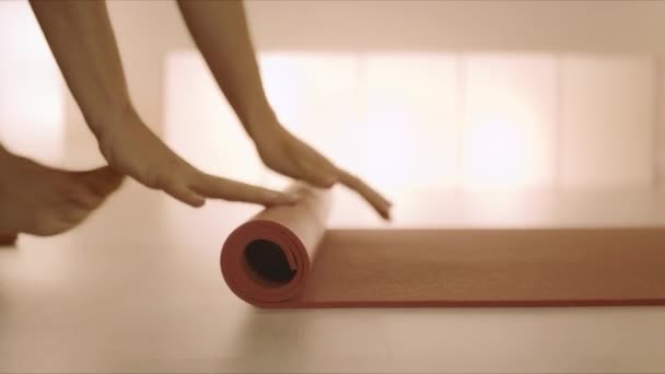 Vrouw handen oprollen yoga mat na de training.Girl vouwen fitness mat op de vloer — Stockvideo