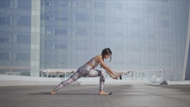 Woman standing in warrior pose at street. Girl practicing yoga on city street — Stock Video