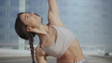 Kadın sokakta ters savaşçı yoga pozu veriyor. Dışarıda elini uzatan bir kadın.
