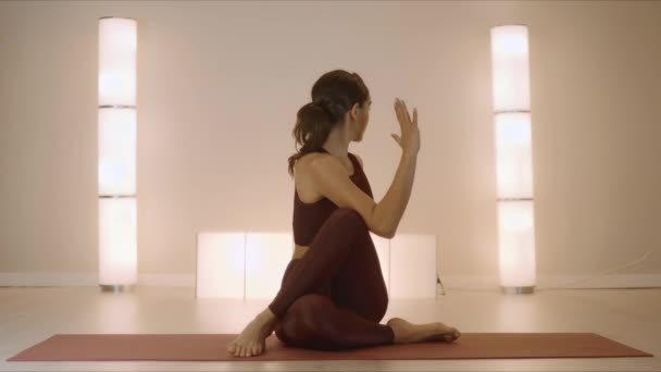 Žena sedící s páteří pózuje na rohožce. Přizpůsobit dívka představení jóga ve studiu — Stock video