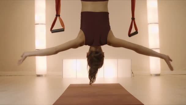 Sportiva che fa manubrio su tappetino da yoga. Donna appesa a testa in giù in amaca — Video Stock