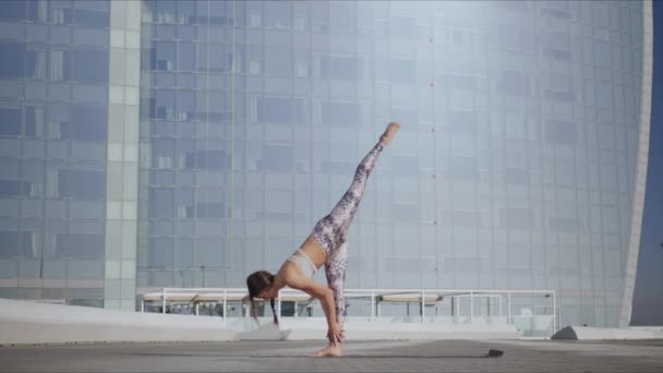 Vrouw doet neerwaarts gerichte honden houding. Meisje het uitvoeren van yoga oefeningen op straat — Stockvideo