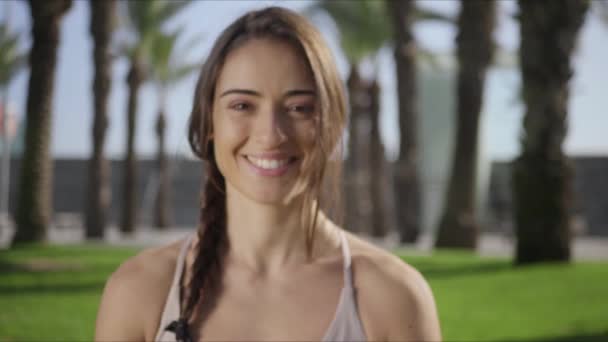 Mujer mirando a la cámara en el parque después del entrenamiento de yoga. Chica sentada en el parque — Vídeo de stock