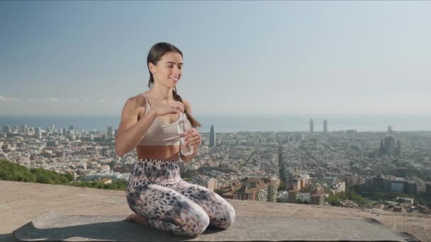 Mujer abriendo botella con agua al aire libre. Chica bebiendo agua en el mirador — Vídeos de Stock