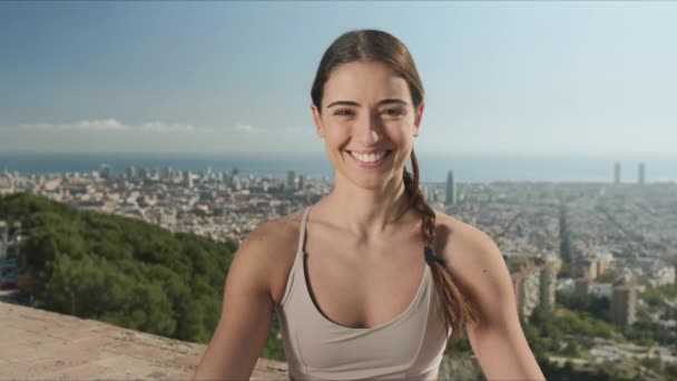Chica sentada en la estera después del entrenamiento de yoga. Mujer sonriente mirando a la cámara al aire libre — Vídeos de Stock