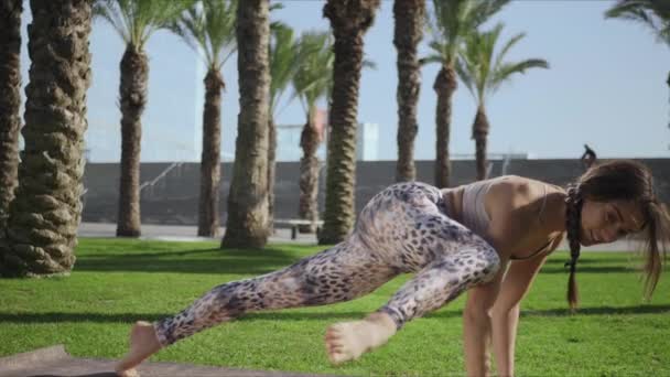 Mujer estirando el cuerpo en el parque. Chica practicante sabio koundiya pose en estera de yoga — Vídeos de Stock